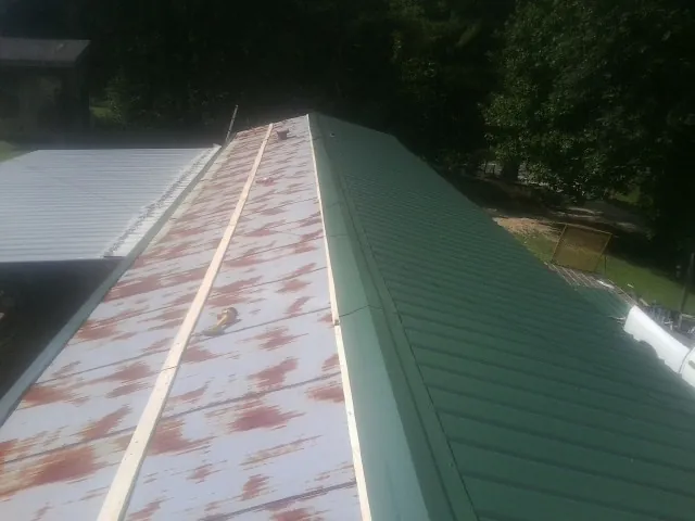 Old rusted panels beside newly installed green metal roofing — Wind Damage Roof Repair by Roofing Brothers in Park Hills
