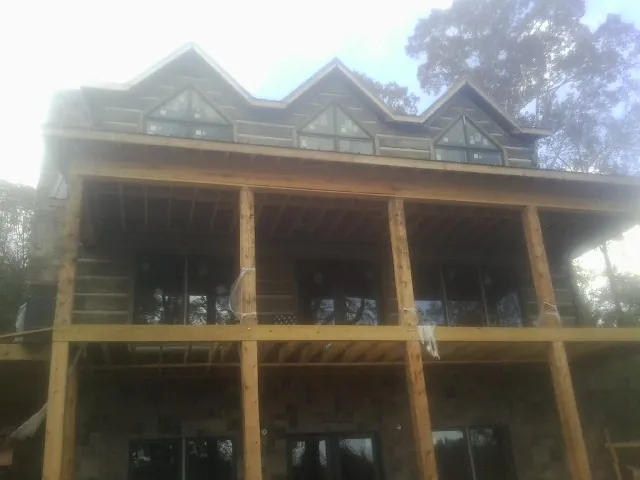 Dormers and porch framing on a large log home under construction — Roof Coating work by our crew in Park Hills