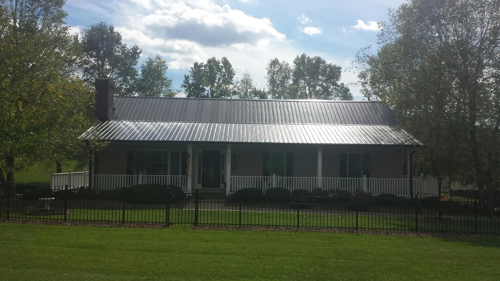 Gray metal roof on a brick ranch with a full width front porch — Gutter Guard Installation work by our crew in Park Hills