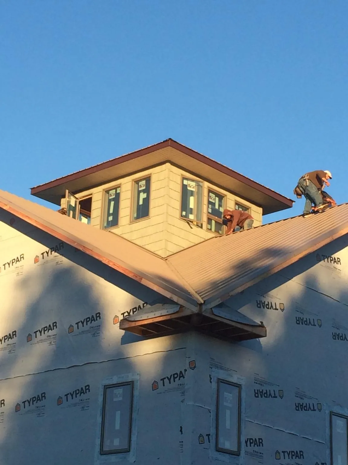 Roofers working around a rooftop cupola on a new metal roof at sunset — Roof Waterproofing in Park Hills by Roofing Brothers